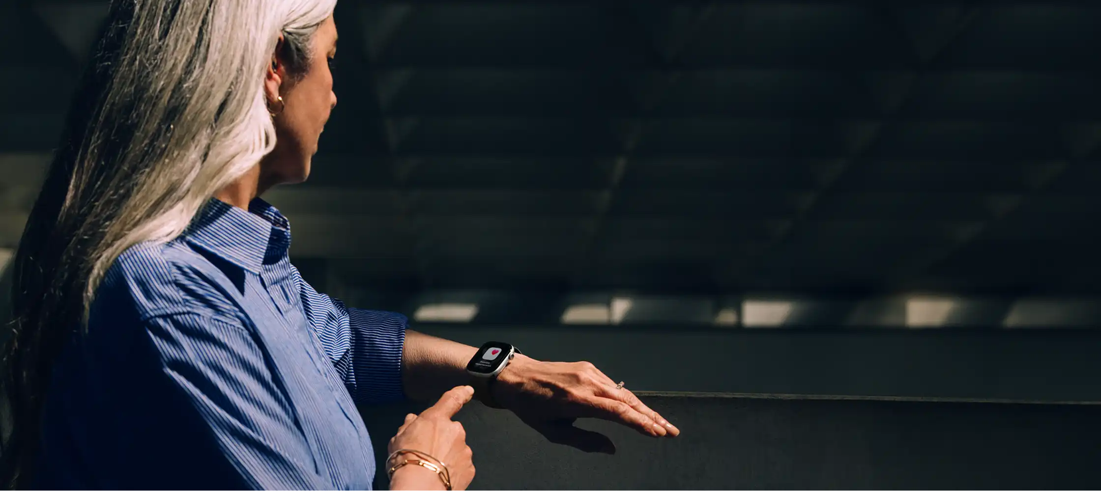 Egy hölgy a bal karját nézi, amin az Apple Watch található