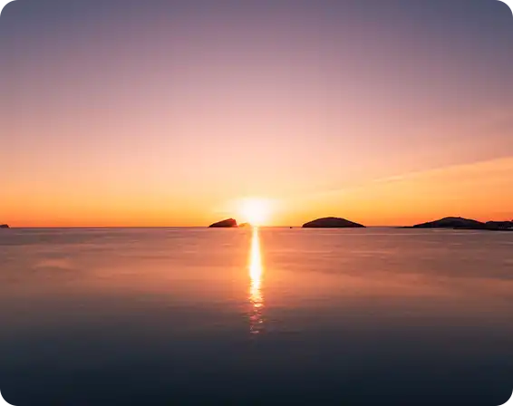 Naplemente nyugodt tengeren, a nap fénye a vízen tükröződik.